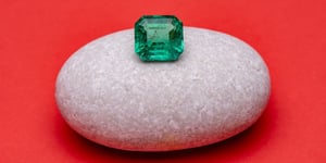 A large emerald ready to be placed as a center stone in an alternative engagement ring